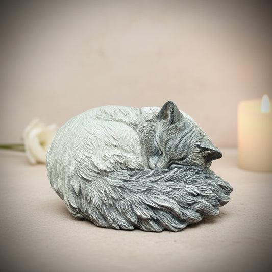 Statue of a sleeping cat on a wooden surface with a blurred green background
